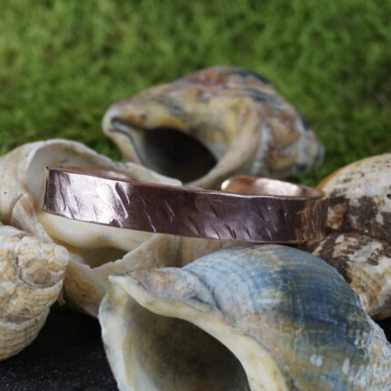 Der "Draíocht Éireann" Armreif ist ein meisterhaft handgefertigtes Kupferstück, das die keltische Tradition zelebriert. Mit einem Innendurchmesser von 7 cm und kunstvollen Hammerschlägen verziert, vereint er rustikale Schönheit mit zeitlosem Design. Inspiriert von keltischer Handwerkskunst symbolisiert er nicht nur Stärke und Tapferkeit, sondern dient auch als spiritueller Talisman. Der Name "Draíocht Éireann" – Magie Irlands – unterstreicht die mystische Verbindung zu den keltischen Wurzeln. Ein einzigartiges Schmuckstück, das Tradition und Moderne in perfekter Harmonie vereint