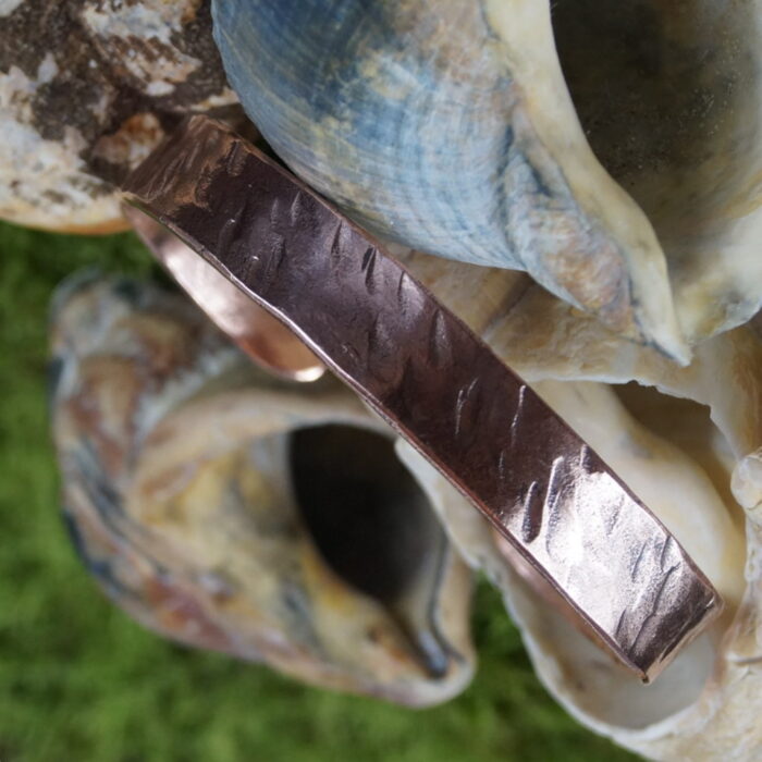 Der "Draíocht Éireann" Armreif ist ein meisterhaft handgefertigtes Kupferstück, das die keltische Tradition zelebriert. Mit einem Innendurchmesser von 7 cm und kunstvollen Hammerschlägen verziert, vereint er rustikale Schönheit mit zeitlosem Design. Inspiriert von keltischer Handwerkskunst symbolisiert er nicht nur Stärke und Tapferkeit, sondern dient auch als spiritueller Talisman. Der Name "Draíocht Éireann" – Magie Irlands – unterstreicht die mystische Verbindung zu den keltischen Wurzeln. Ein einzigartiges Schmuckstück, das Tradition und Moderne in perfekter Harmonie vereint.