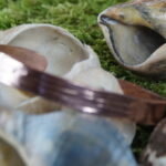 In der winzigen Welt der Kobolde entstand der Armreif – ein wahres Meisterstück von handwerklich versierten Koboldenhänden. Mit einem Innendurchmesser von 6,7 cm, einem federleichten Gewicht von nur 16 Gramm, einer Materialstärke von gerade einmal 0,2 cm und einer bezaubernden Breite von 1 cm wird er zum magischen Ergebnis koboldischer Kupferkünste. Die klugen Kobolde haben sorgfältig gesammeltes und eingeschmolzenes Kupfer zu einem funkelnden Juwel geformt. Poliert bis zum Glänzen und zart mit Hammerschlägen verziert, tanzt der Reif nun in geheimnisvoller Eleganz – ein verlockendes Stück Koboldenzauber, bereit, die Welt zu verzaubern!