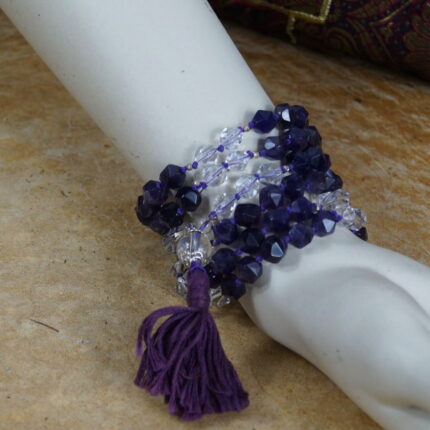 In der Bergstille, tief meditierend, vereine ich mich mit der Natur. Fühlingsgrün umhüllt mich, die Cosmic Clarity Mala in meiner Linken. Die Sonne streichelt, die Luft ist rein. Die Mala – Amethyst, Bergkristall, Silber – warm und kühl zugleich. Ein magisches Tanzspiel von Licht und Dunkelheit, Tiefe und Klarheit. Inmitten der Bergspitzen entfaltet die Mala geheimnisvolle Geschichten des Kosmos. Ein stiller Zeuge der Bergweisheit, getränkt von Sonnenwärme und Bergklarheit