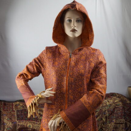 In einem lebendigen Kleiderschrank erzählt der Mantel seine Geschichte: "Ich bin jugendlich, frech und bereit, die Welt zu erobern. Mit floralen und Paisley Mustern, in gedecktem Orange und harmonischem Creme Orange, bin ich ein lebendiges Unikat mit handwerklichen Narben. Nicht nur für den Kleiderschrank gemacht, sondern für Straßen und unvergessliche Abenteuer. Mein Stoff trägt Leidenschaft und Freiheit. Ich bin der freigeistige Träumer, bereit, die Welt mit Stil zu erobern."